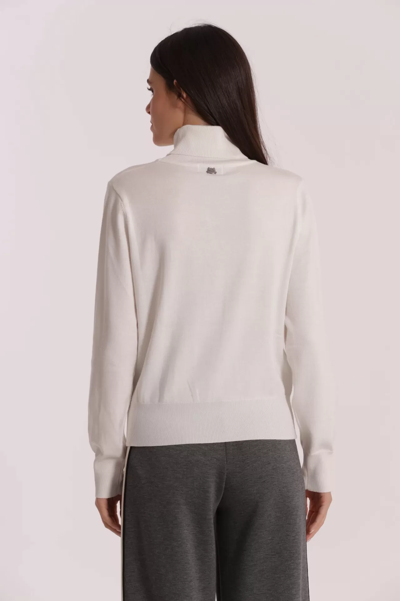 Camisola branca de gola alta vista de costas com calças cinzentas