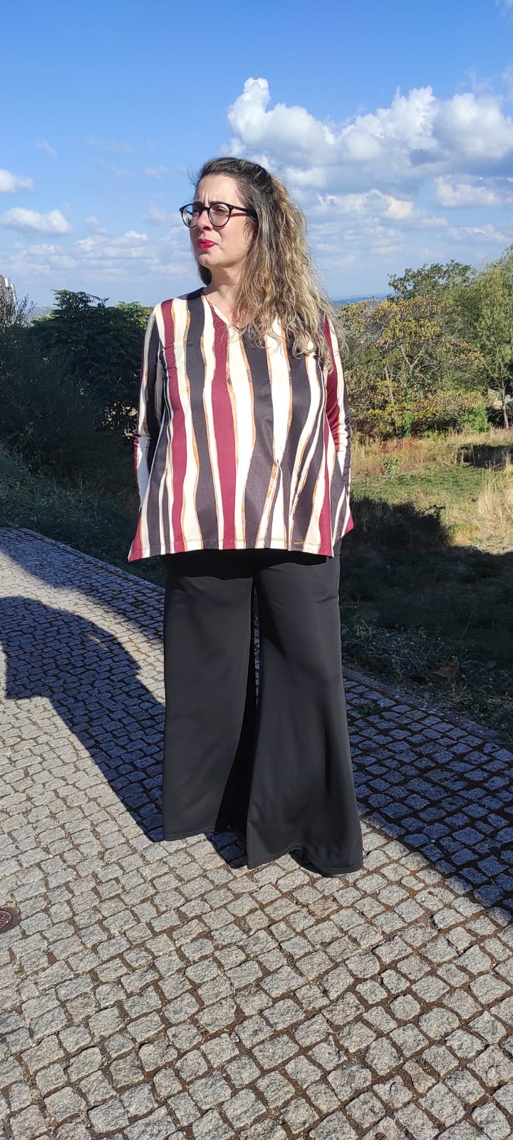Mulher com blusa de riscas coloridas e calças pretas ao ar livre