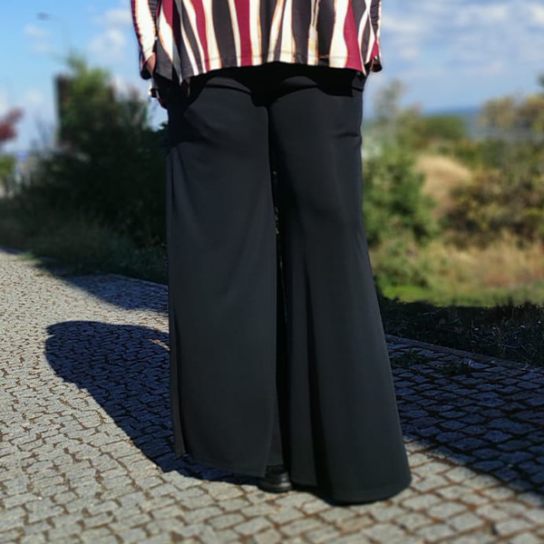 Calças largas pretas em tecido fluído em ambiente exterior