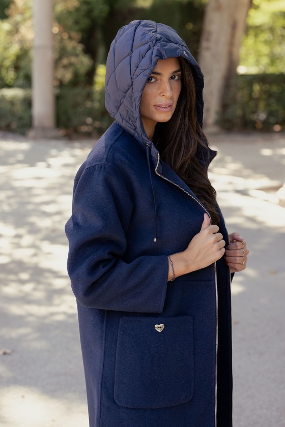 Mulher a usar casaco azul escuro com capuz acolchoado e bolso com botão em forma de coração