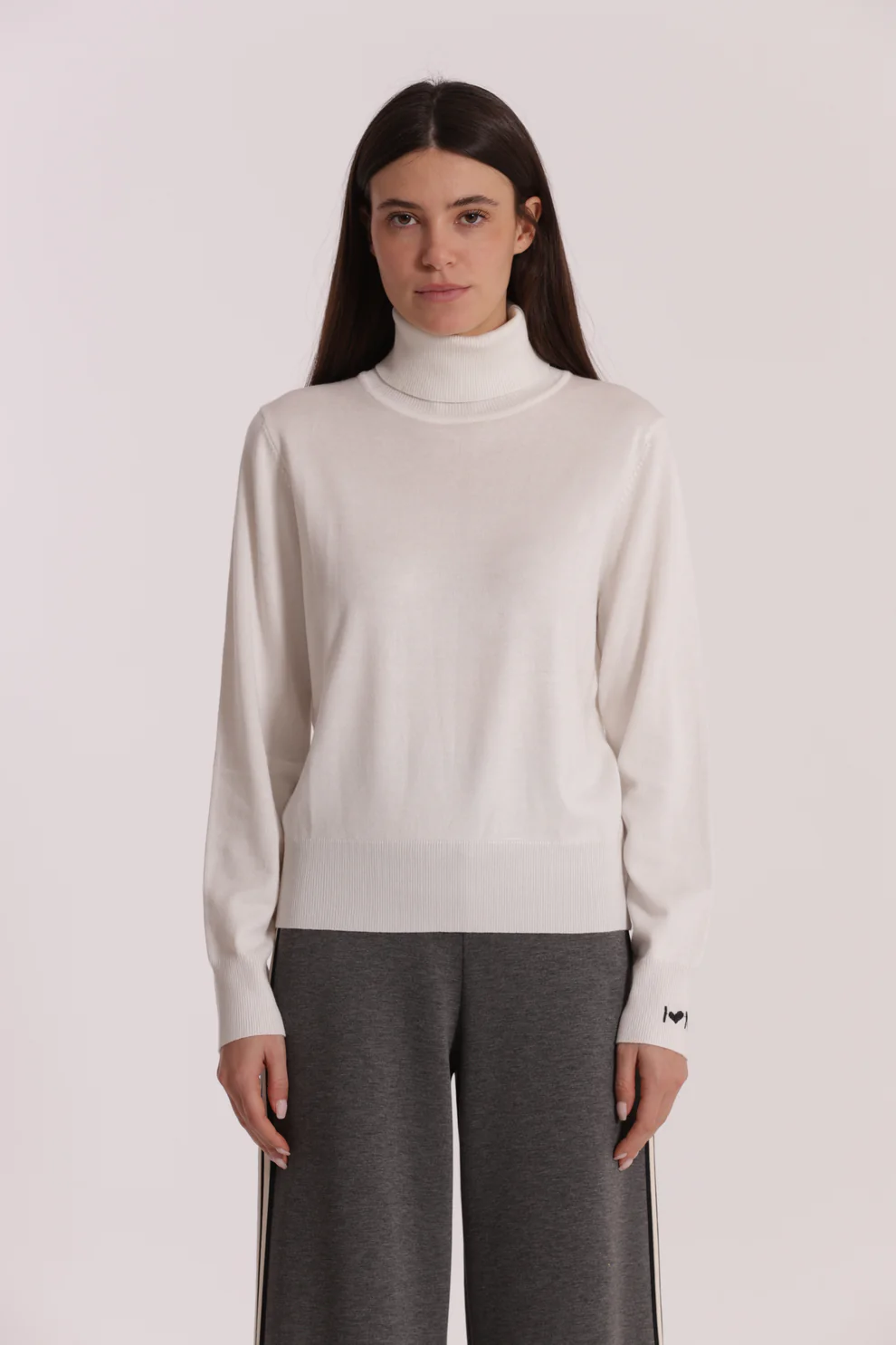 Camisola de gola alta branca com calças cinzentas largas