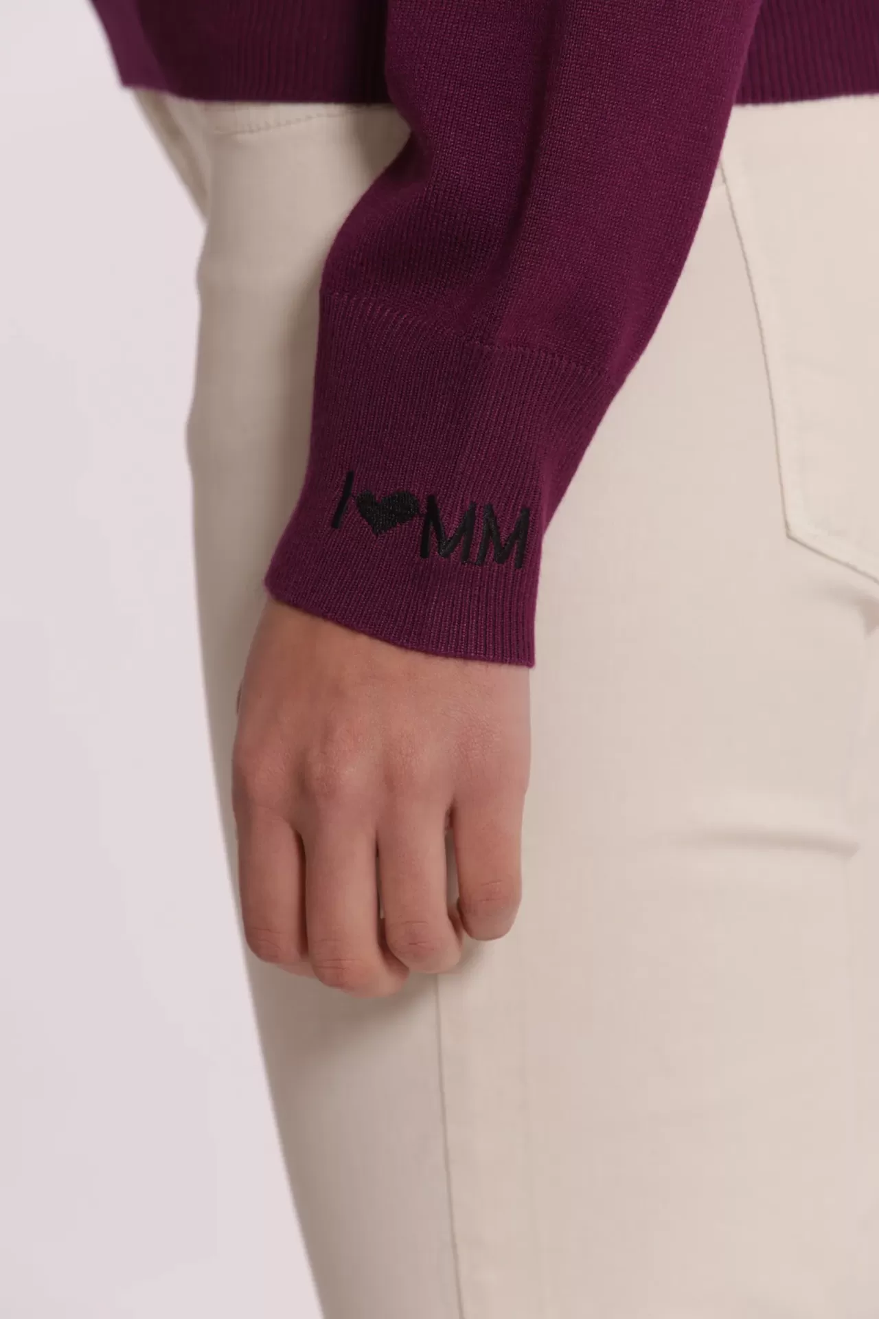 Punho de camisola roxa com detalhe bordado em preto 'I ♥ MM' e calças creme