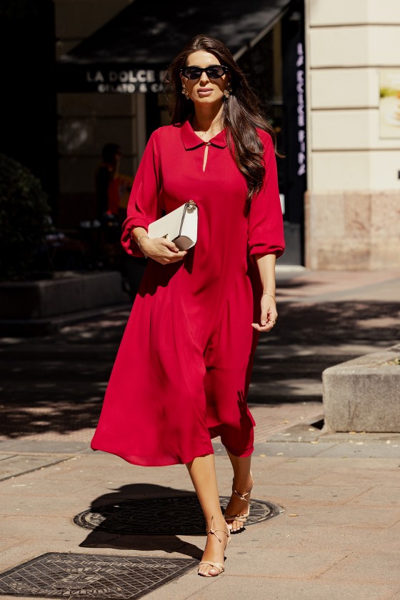 Mulher com vestido midi vermelho e sandálias bege a andar na rua