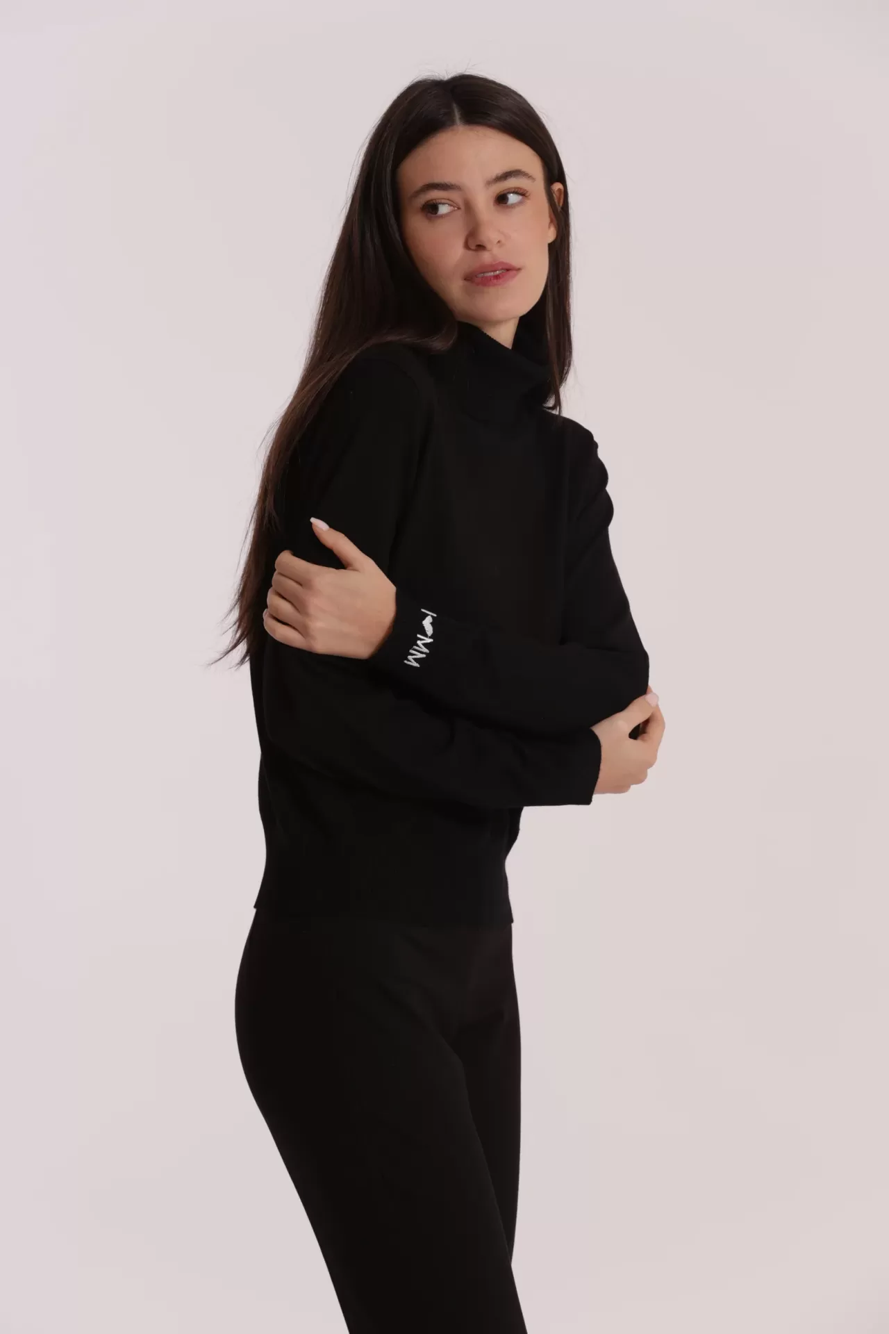 Mulher a usar camisola preta de gola alta e calças pretas