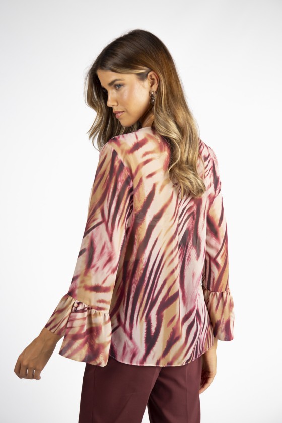 Blusa feminina com padrão abstracto em tons de rosa e castanho e mangas com folhos vista de costas.