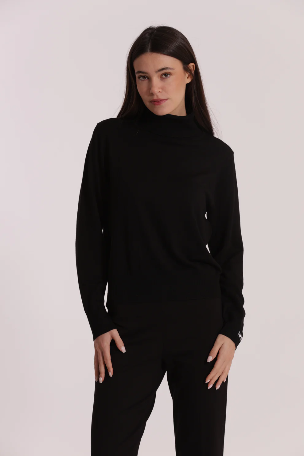 Mulher com camisola preta de gola alta e calças pretas