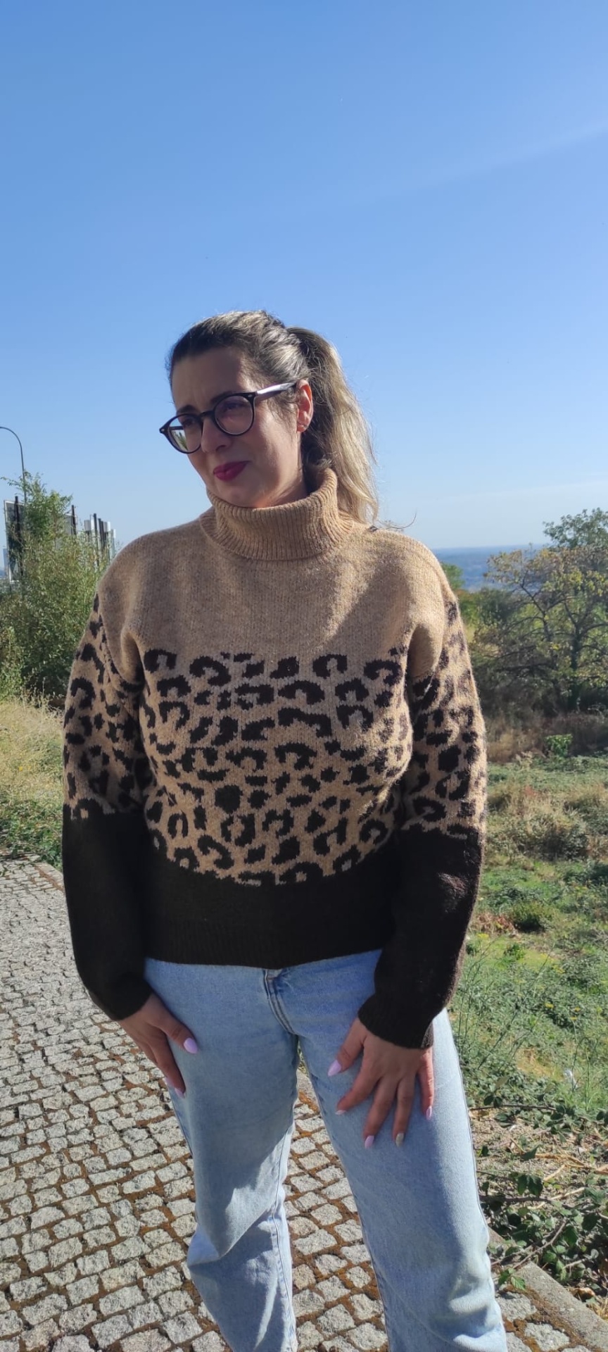 Mulher com camisola de malha animal print e calças de ganga ao ar livre