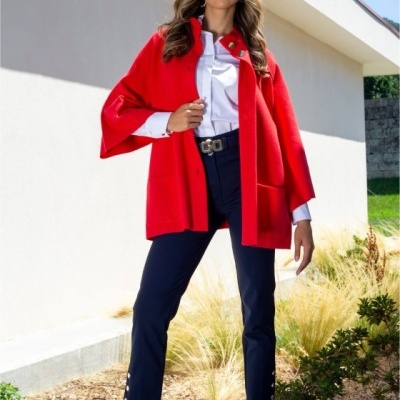 Mulher com casaco vermelho, camisa branca, calças azul-escuras e sapatos vermelhos ao ar livre