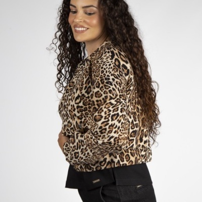 Mulher de perfil com casaco de padrão de pele de leopardo e calças pretas