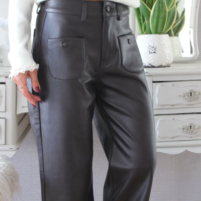 Calças pretas de couro sintético com bolsos frontais e camisa branca com renda nas mangas