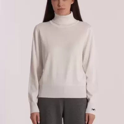 Camisola de gola alta branca com calças cinzentas largas