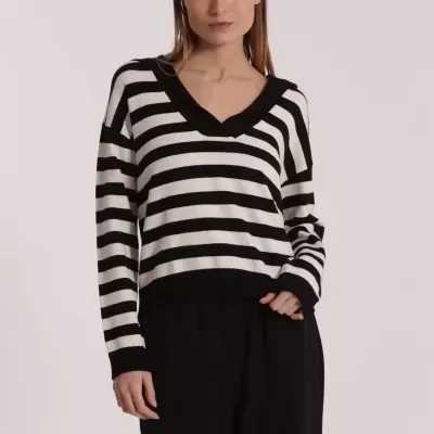 Mulher a vestir sweater riscas preto e branco com gola em V e calças pretas