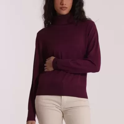 Mulher de cabelo escuro com camisola de gola alta vinho e calças claras