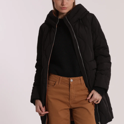 Mulher com casaco acolchoado preto, camisola preta e calças castanhas