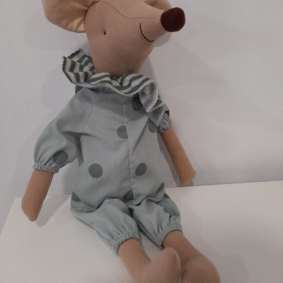 Boneco de peluche em forma de rato com roupa cinza sentado numa superfície