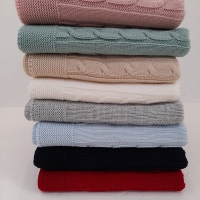 Pilha de mantas de malha em várias cores sobre superfície branca