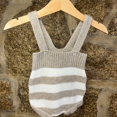 Macacão bebé de malha bege e branco listrado em cabide de madeira