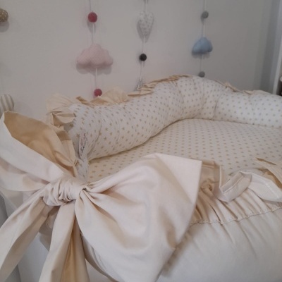 Ninho de bebé branco e bege com laços e móbile de nuvens e luas pastel