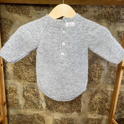 Camisola de malha cinzenta para bebé com botões e etiqueta colorida pendurada num cabide