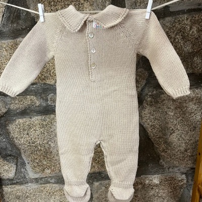 Macacão de bebé em malha bege claro com gola e botões pendurado num varal