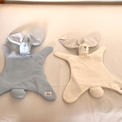 Panos de bebê em forma de coelho cinzento e creme sobre fundo claro