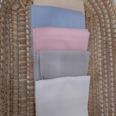 Tecidos dobrados de várias cores sobre uma cesta de fibras naturais.