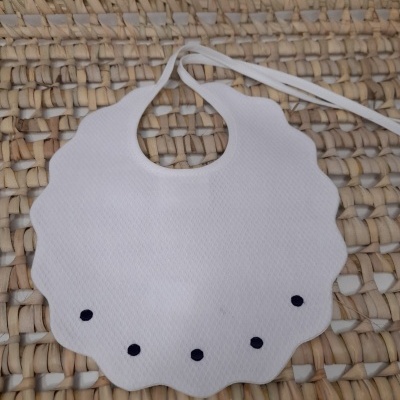 Babete branco com pontos pretos em superfície de palha entrelaçada