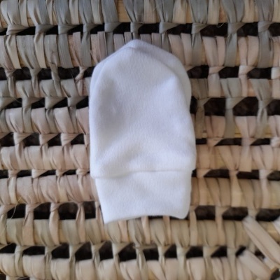 luva branca para bebé sobre superfície de palha entrelaçada