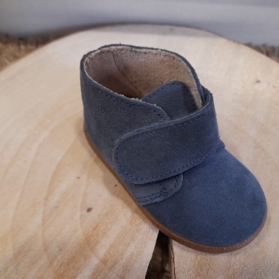 Bota infantil azul de camurça com velcro sobre tábuas de madeira