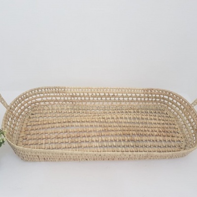 Cesto retangular de trançado natural com alças e planta verde num vaso pequeno