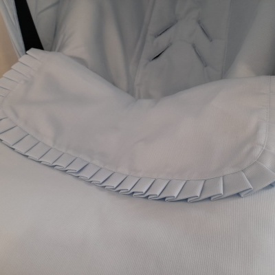tecido branco com borda pregueada sobre tecido cinza claro acolchoado