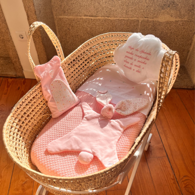 Berço de bebé com manta e almofada cor-de-rosa em verga