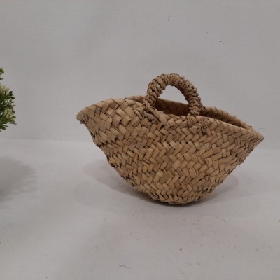 Cesto decorativo em palha natural com padrão trançado e planta verde ao lado