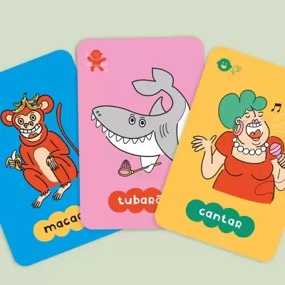 Cartas coloridas com desenhos de um macaco, tubarão e mulher a cantar com palavras em Português.