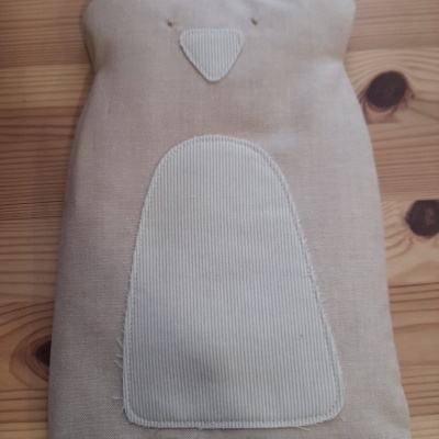 Almofada decorativa em tecido bege claro em forma de animal com detalhes bordados