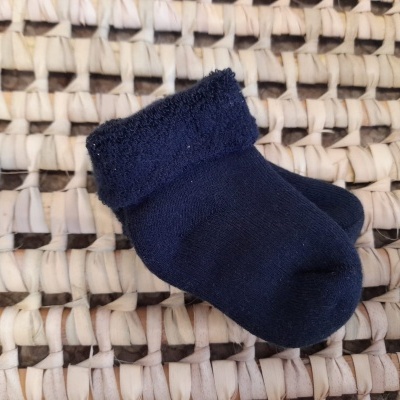 Meia azul escura com dobra felpuda sobre superfície trançada