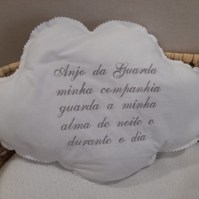 Almofada branca em forma de nuvem com texto bordado em português