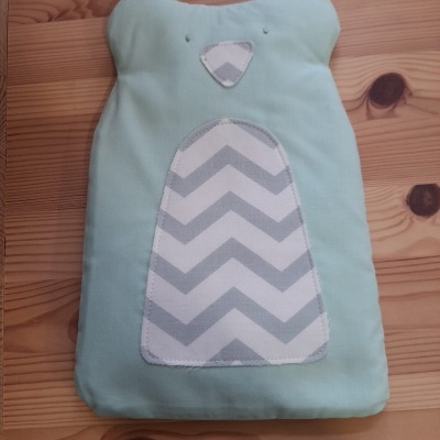 Travesseiro em forma de urso com padrão de ziguezague cinza e branco sobre mesa de madeira clara