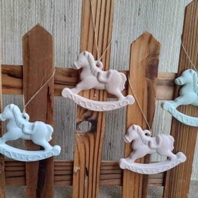 Enfeites de cavalinho de balanço azul e rosa pendurados em cerca de madeira rústica