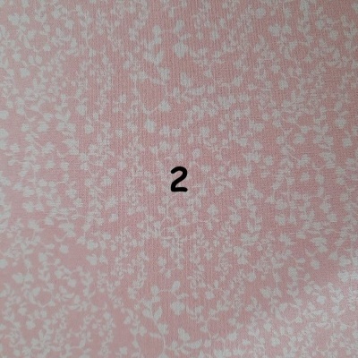 Tecido cor-de-rosa claro com padrão de pequenas folhas brancas e número 2 preto