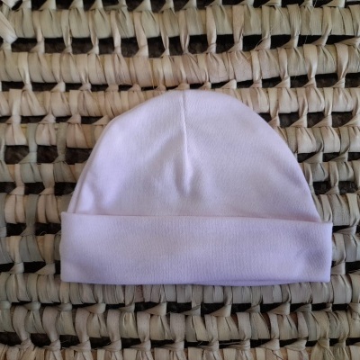 Gorro branco de tecido macio sobre superfície tecida entrelaçada