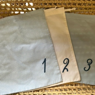 Três saquetas de pano numeradas sobre superfície de palha
