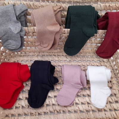 Oito pares de meias coloridas para bebé num cesto de fibras naturais