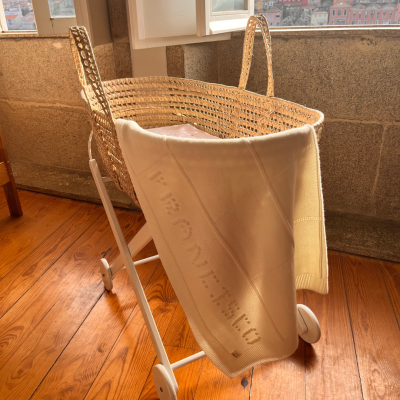 Berço de bebé com manta pendurada em madeira e verga natural