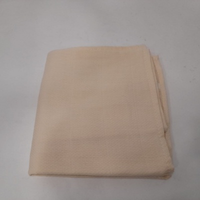 Toalha ou tecido bege claro dobrado sobre superfície branca