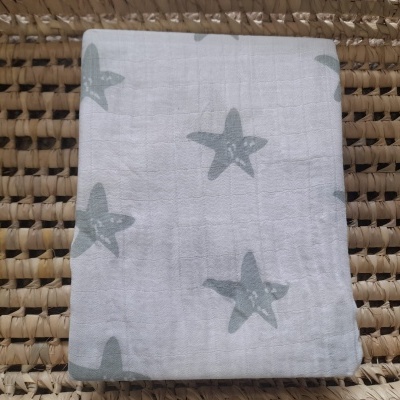 Fralda branca com estrelas cinzentas sobre superfície de rattan