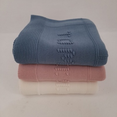 Três mantas em malha azul, rosa e creme empilhadas