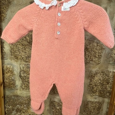 Macacão de bebé salmão com gola de renda branca pendurado em cabide
