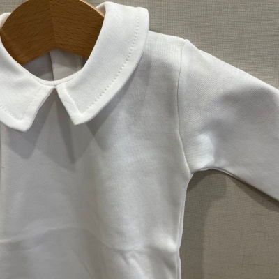 Roupa branca de bebé com gola redonda e manga comprida pendurada num cabide