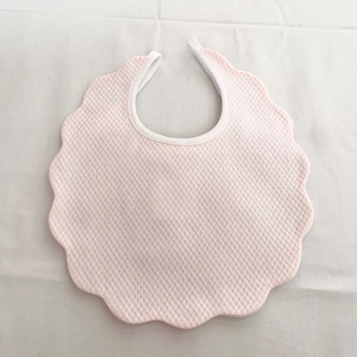 Babete rosa claro com bordas onduladas e textura acolchoada